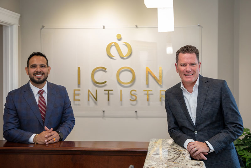 Doctors smiling in front of the Icon Dentistry sign